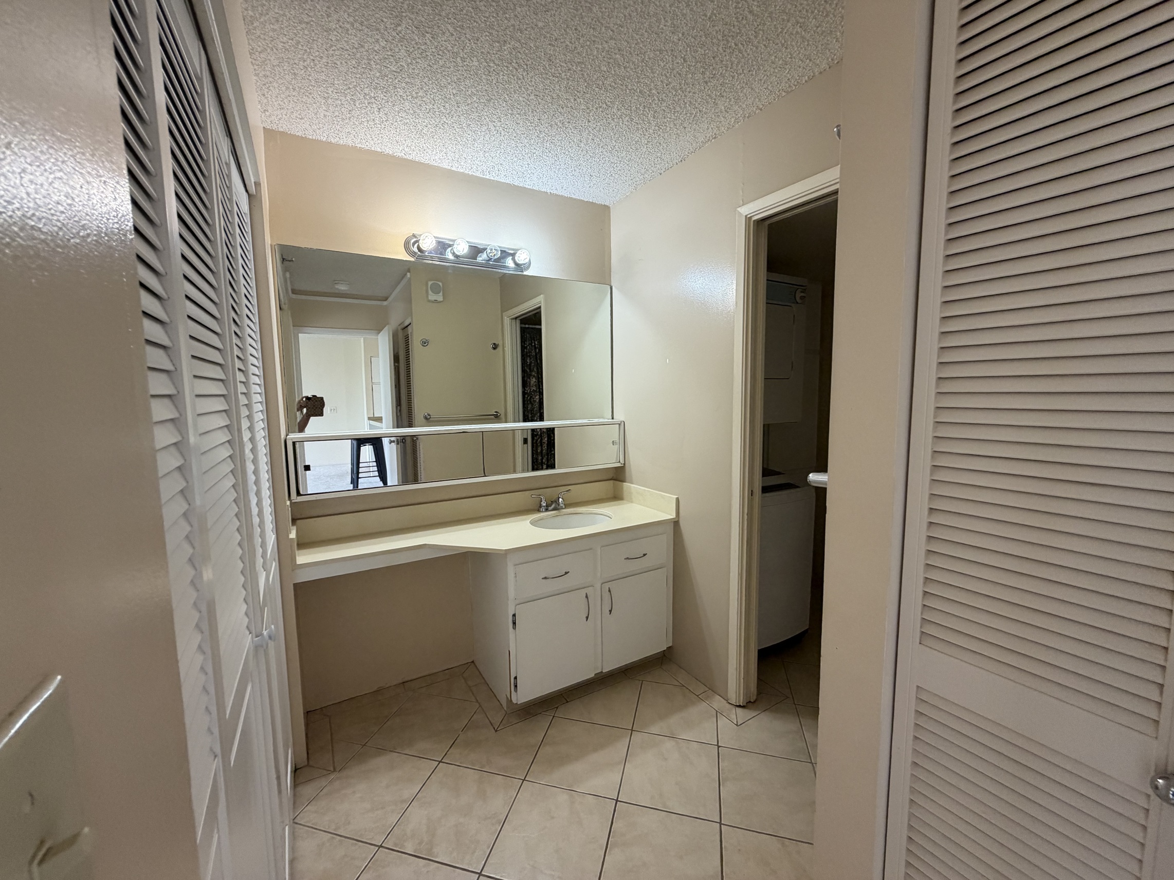 A bathroom with a sink, mirror, and cabinets.